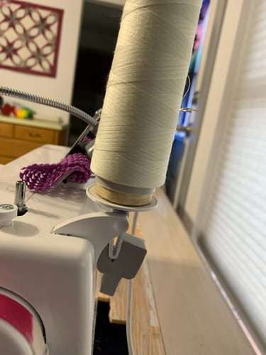 Close-up: Customer's modified Horizontal Thread Holder on a sewing machine, holding a spool of white thread.