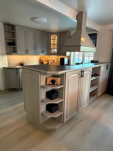 Kundens klassiske håndtak i sort matt montert på lysegrå kjøkkenskap.