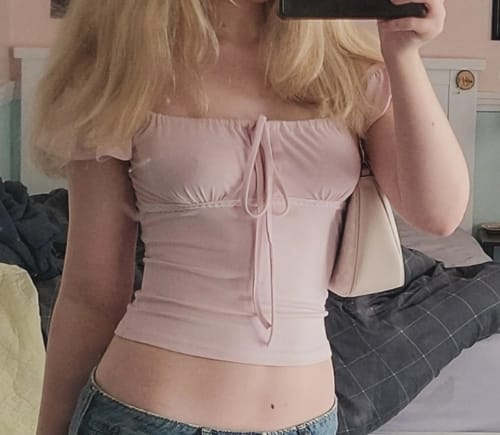 Customer wearing the cropped pink Arlyse Ruffle Top with flutter sleeves and a tie front.