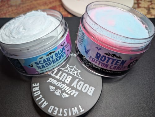 Customer's open jars of 'Scary Blue Raspberry' and 'Rotten Cotton Candy' whipped body butters on a table.