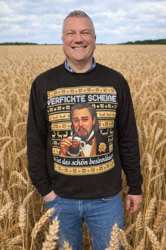 Ein Kunde trägt den schwarzen Premium Weihnachts-Sweater von SCHÖN BESINNLICH in einem Feld.