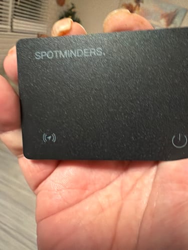 Customer holding the black SPOTMINDERS. Tracking Card in the palm of their hand.