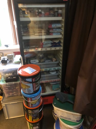 Recensent toont opgestapelde emmers WONDER RANGE MIX voor een volle koelkast met visvoer.