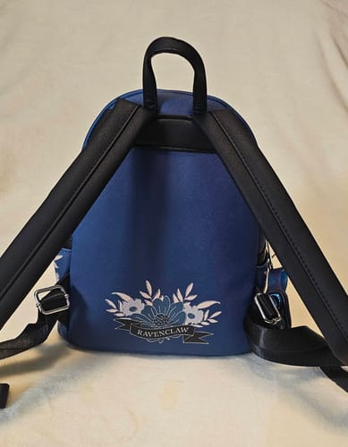 Reviewer's blue Ravenclaw backpack, showing the back with a floral design and 'Ravenclaw' banner.