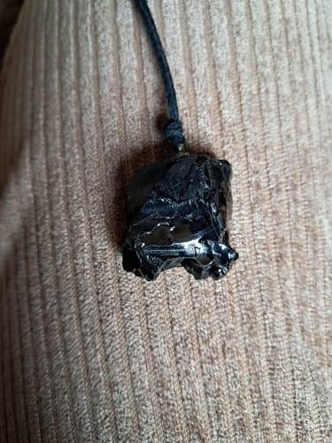 Avis d'un client : gros plan sur le pendentif en Shungite élite brut et noir porté.