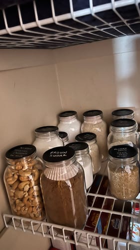 Customer's organized pantry with several glass jars using the labeled Chalkboard Top Mason Jar Lids.