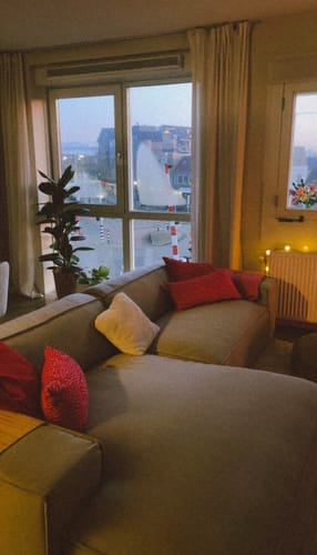 Recensent toont de beige Chunky hoekbank in een gezellig verlichte woonkamer bij het raam.