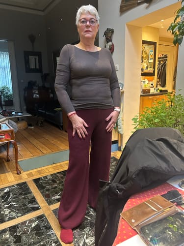 Customer facing forward to show the fit of the Espresso Brown Mae Featherweight Boatneck Top in a home setting.