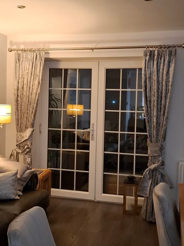 Customer's long curtains made from silvery Marble Crushed Velvet Fabric, framing a set of French doors in a living room.