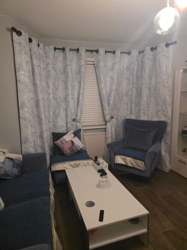 Customer's living room with long curtains made from the patterned Dusty Trees Furnishing Fabric.