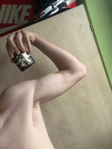 Reviewer holds the black jar of Ashwagandha KSM-66 while flexing their arm, showing the product.