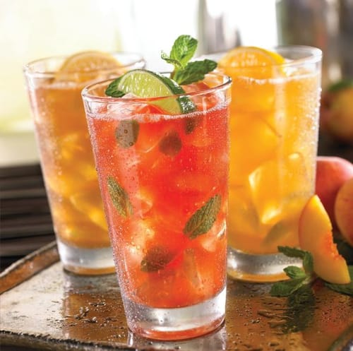 Customer's refreshing Peach & Hibiscus Iced Tea served in tall glasses with ice, mint, and fruit garnishes.