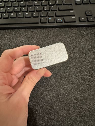 Customer holding the closed, silver Nano Case, showing the textured top.