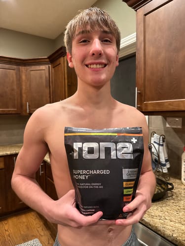 Customer smiling and holding a bag of VARIETY PACK SuperCharged Honey.