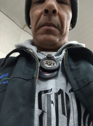 Reviewer wearing the dark brown genuine leather medallion holder as a necklace over a hoodie.