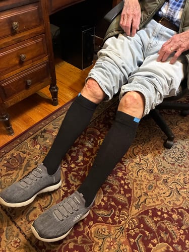 Customer sitting in a chair wearing black Performance Eucalyptus Compression Socks with jeans and sneakers.