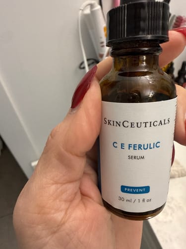 Customer holding a brown bottle of SkinCeuticals C E Ferulic serum.