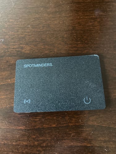 Customer's black SPOTMINDERS tracking card lying flat on a dark wooden surface.
