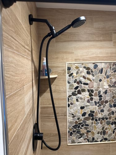 Reviewer's black 1-Handle Shower System installed in a modern, wood-grain tiled shower.