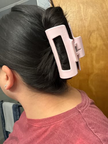 Reviewer's light pink cloud clip holding up thick hair.