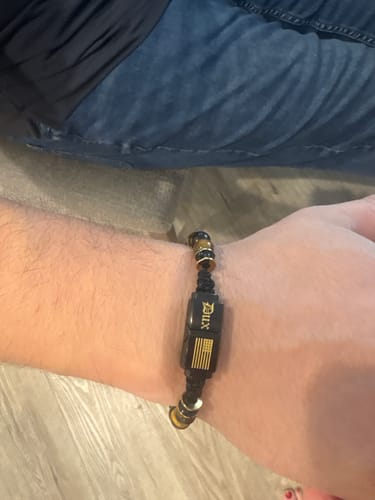 Customer wearing the Nighthawk Tiger's Eye Bracelet, showing the black clasp with gold DUX logo and flag.