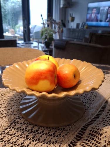 Recensent toont de beige, geribbelde HKliving schaal op een tafel, gevuld met appels.