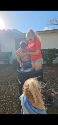 Reviewer's family having fun using the black Ice Pod in a backyard, with a man sitting inside.