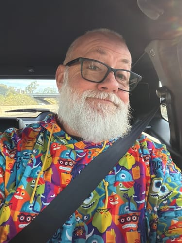 Reviewer smiling in a car while wearing the colorful Monsters, Inc. 'The Scare Floor' Performance Hoodie.