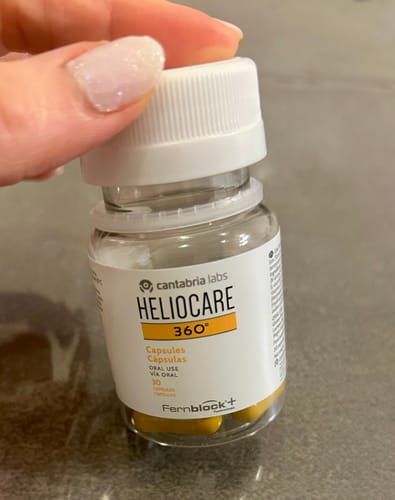 レビューアーがヘリオケア360° ORALのボトルを手に持っている様子。中には黄色いカプセルが見えます。