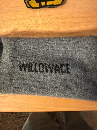 Customer's folded grey Men's Alpaca Socks on a wooden surface, with the brand name visible.