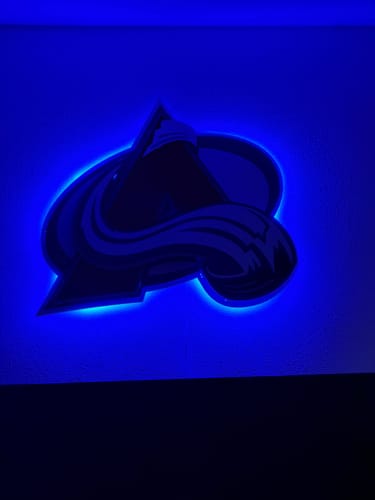 Customer's Colorado Avalanche wall art mounted on a wall, glowing with a bright blue LED backlight.