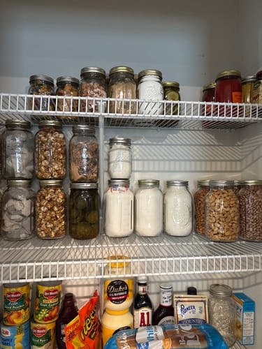 Customer's pantry with shelves of food stored in sealed mason jars, organized using the Mason Genie.