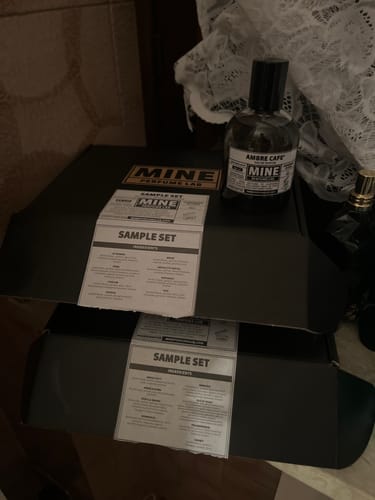 Recensore mostra il flacone di profumo Ambre Cafe e le scatole del Set campioni dolci e calde.