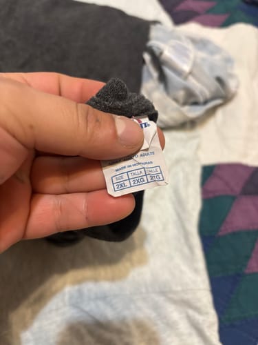 Close-up of a customer holding the size tag of a dark vintage t-shirt, showing size 2XL.