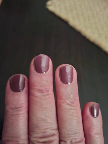 Nahaufnahme der Hand einer Kundin mit aufgetragenen, glänzenden Berry Merlot UV-Gel-Folien.