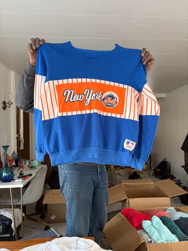 Customer holding a blue B-Grade sweatshirt with a damaged, cut-out neck, illustrating the product's condition.