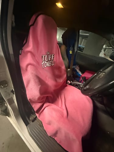 Customer's pink Tuff Towel waterproof seat cover fitted on the driver's seat of a car.