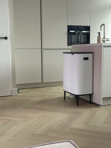 Recensent toont de witte Brabantia Bo Touch Bin in een moderne keuken.