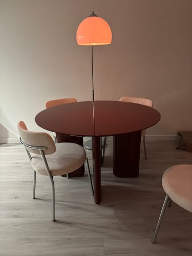 Klantfoto van de wijnrode Glinta eettafel, opgesteld in een eetkamer met stoelen en een lamp.