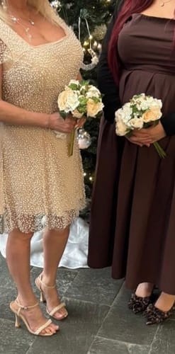 Customer and another person holding matching Bridal Rose with Pearls White Bouquets at an event.