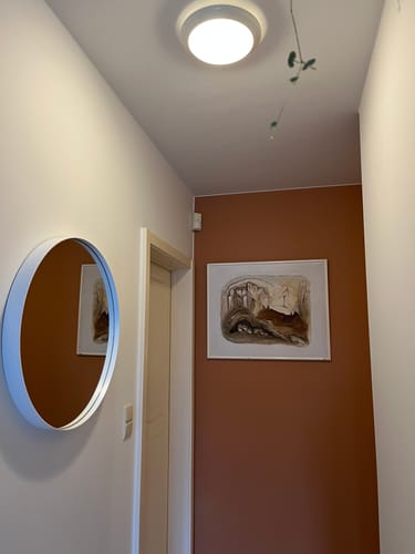 Recensent heeft de ronde, witte Spinder Design Donna spiegel in een hal hangen.