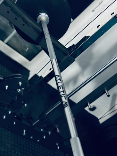 Rezensentenfoto der Sigma Langhantel aus Chrom, die in einem dunklen Homegym-Rack platziert ist.