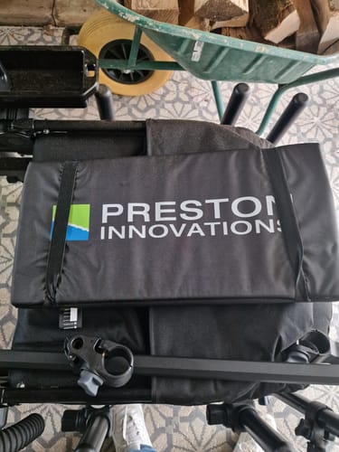 Beoordelaar toont de opgevouwen, zwarte Fold Away Unhooking Mat op een visstoel.