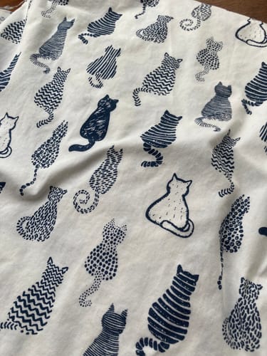 Customer's close-up of the Striped Cats Cotton Poplin Fabric, showing the stylish dark blue cat print on a white background.