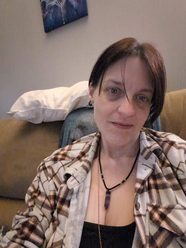 Reviewer wearing the Natural Fluorite Necklace, showing the purple crystal on a black cord against their chest.