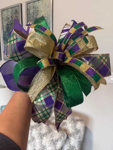 Reviewer holding a large, festive bow with purple, green, and gold ribbons made using the Bow Handbook.