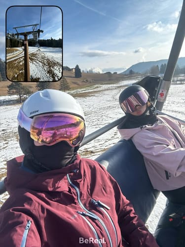 Reviewer wearing the pink waterproof snow jacket while sitting on a ski lift at a sunny ski resort.