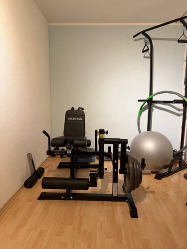 Der montierte schwarze Fullbody Multitrainer eines Kunden in einer Ecke neben anderer Fitnessausrüstung.