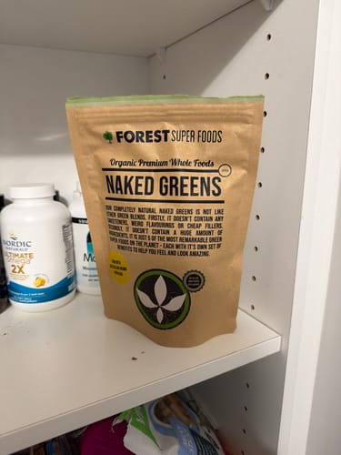 Reviewer's pouch of Naked Greens powder sitting on a white pantry shelf.