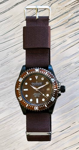 Reviewer's Oceaneva Deep Marine Explorer watch showing the aged bronze dial and a custom reddish-brown NATO strap.